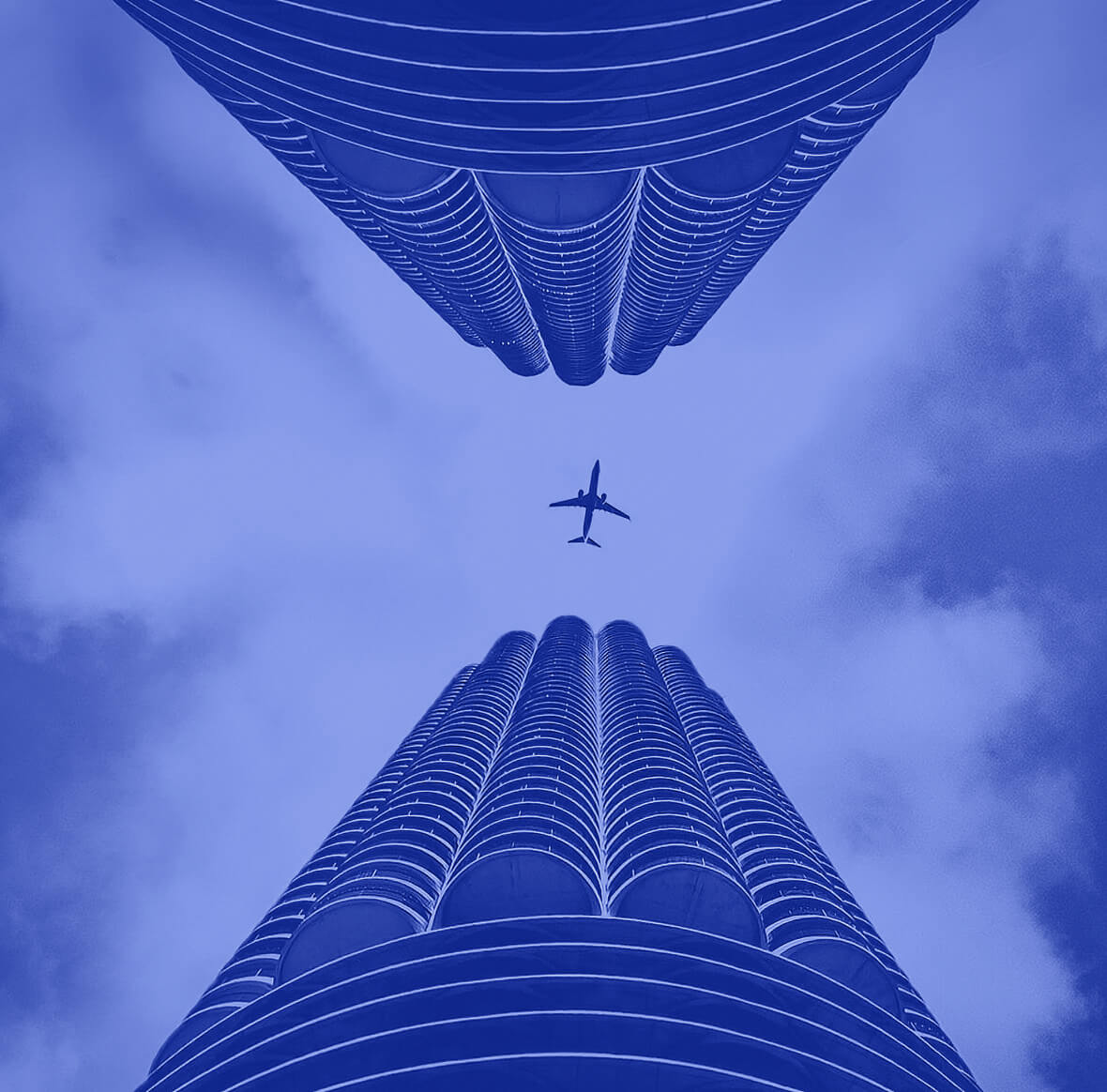 conexion-global-ma-worldwide View from below of two buildings with an airplane crossing the blue sky, representing the global network and M&A Worldwide transactions.